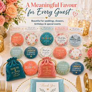 A styled event table display showing a gift set of round thank-you badges and matching drawstring pouches. The set includes multiple colors and floral designs, with teal, coral, pink, and blue badges and pouches arranged on a white table with gold cutlery, flowers, and glassware.