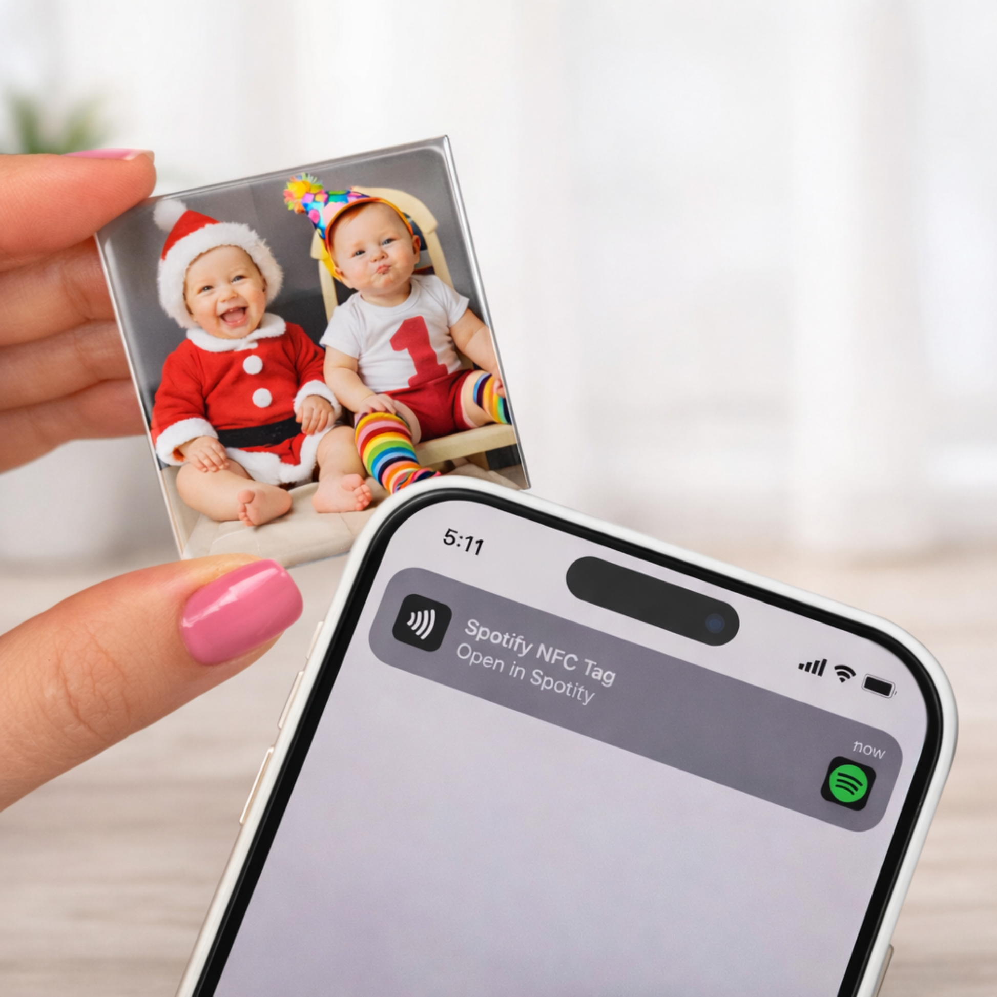 Hand holding a photo of two children next to a smartphone with Spotify app on screen.